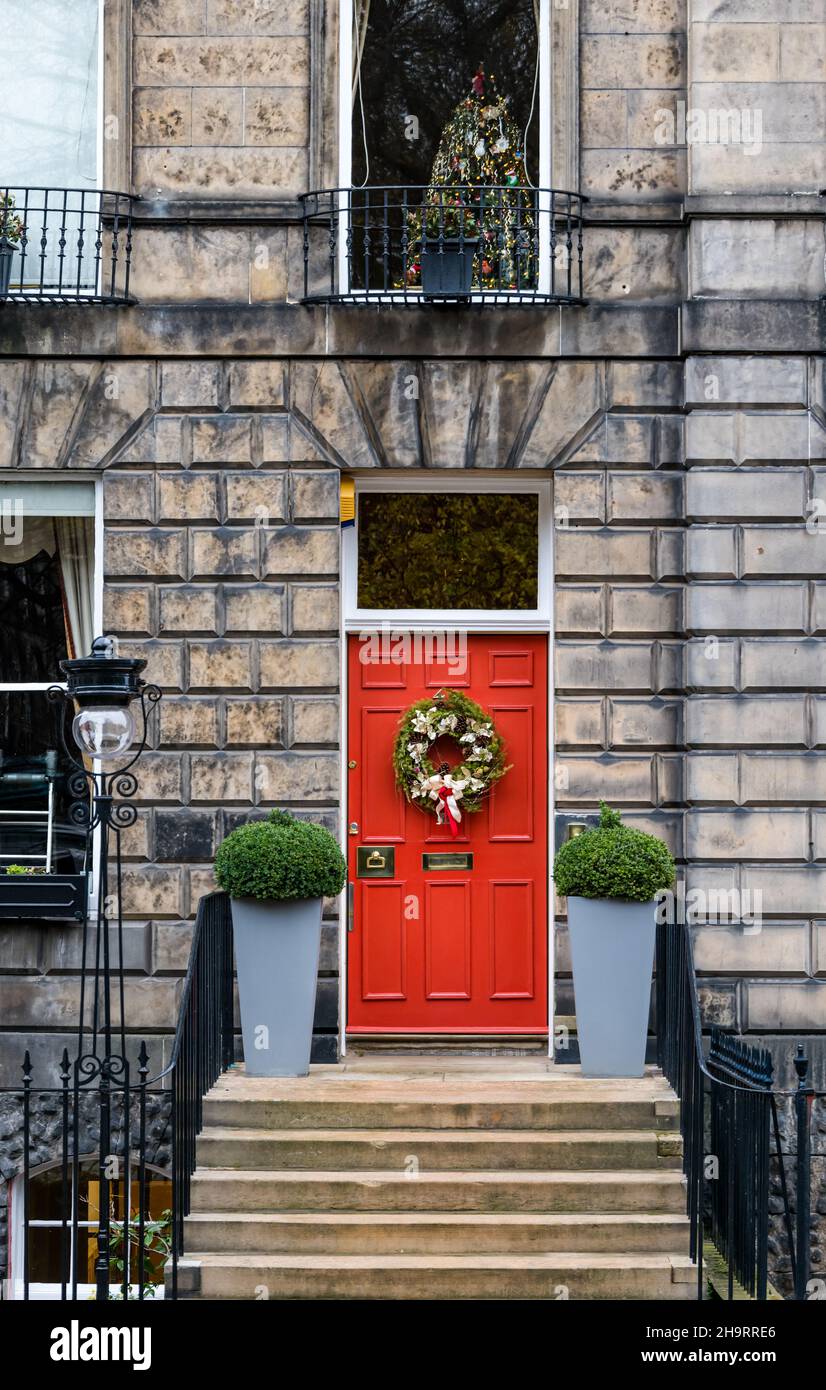 Georgian Stadthaus rot gemalte Haustür mit Weihnachtskranz, Weihnachtsbaum im Fenster und alten Lampenpfosten, Edinburgh New Town, Schottland, Großbritannien Stockfoto