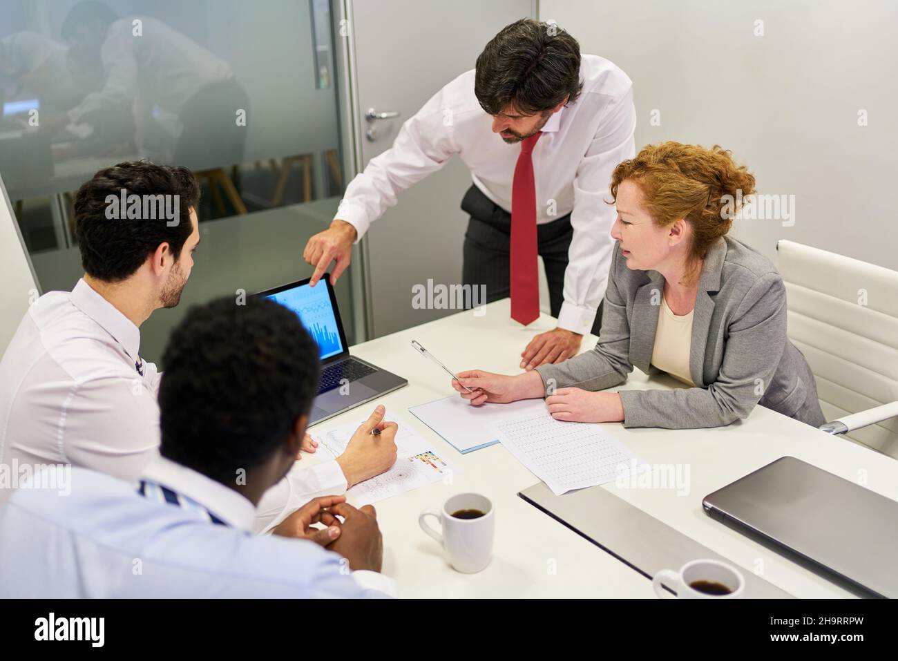 Geschäftsleute, die Finanzanalysen und Strategieplanung am PC mit einem Berater in einem Meeting durchführen Stockfoto