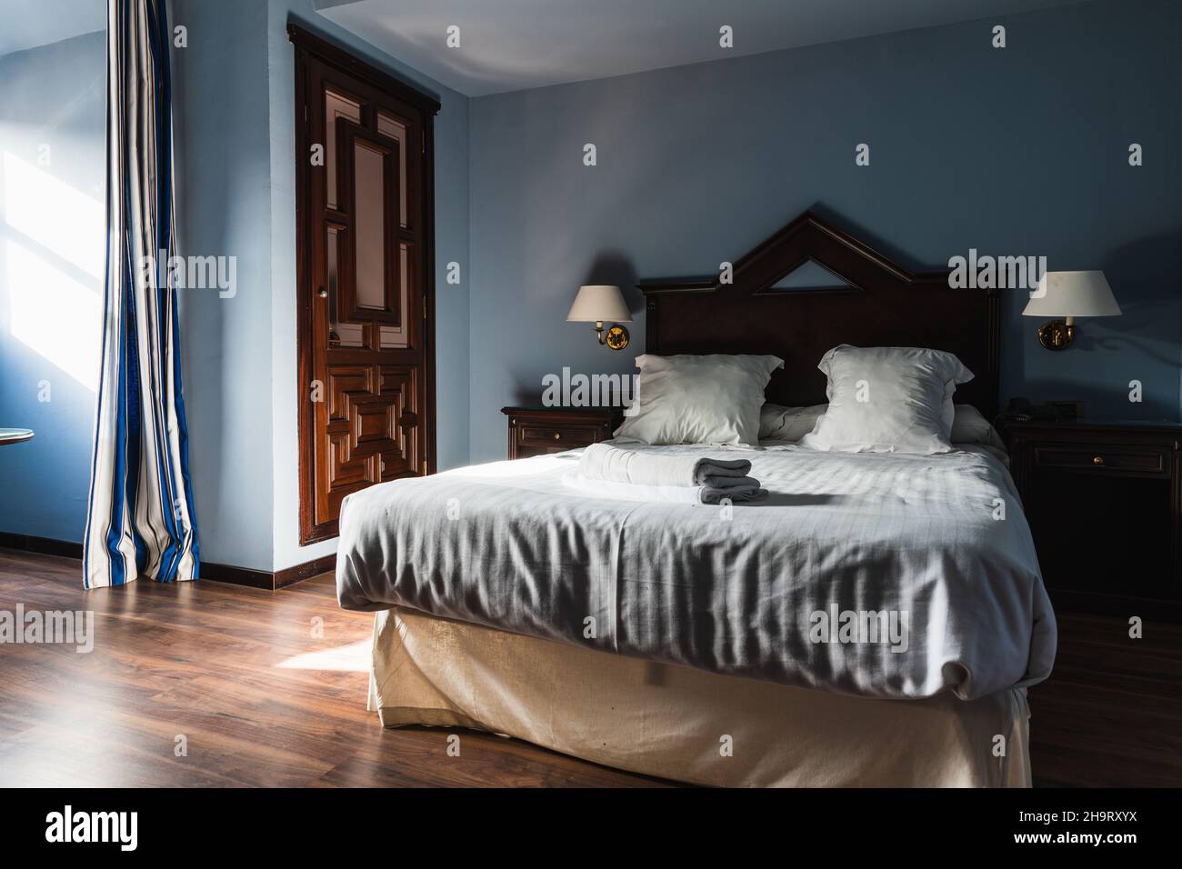Hotelzimmer am Morgen mit Licht, das durch das Fenster kam, das Bett gemacht und die Handtücher zusammengerollt Stockfoto