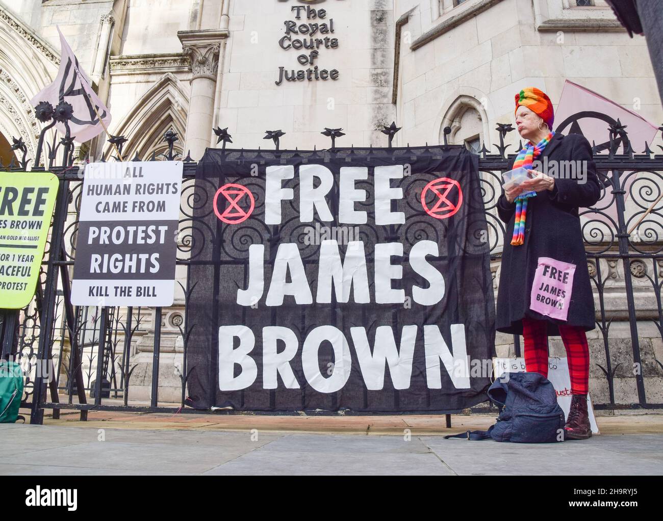 London, Großbritannien. 08th Dez 2021. Während der Demonstration steht ein Protestler neben einem Transparent "Free James Brown".die Demonstranten versammelten sich vor den königlichen Gerichtshöfen, um sich solidarisch mit dem Paralympischen und Extinction Rebellion-Aktivisten James Brown zu zeigen, der gegen seine Verurteilung und Verurteilung appellierte. Er verbüßt derzeit eine einjährige Haftstrafe, weil er am City Airport auf ein Flugzeug klettert, um auf die Klimakrise aufmerksam zu machen. (Foto: Vuk Valcic/SOPA Images/Sipa USA) Quelle: SIPA USA/Alamy Live News Stockfoto