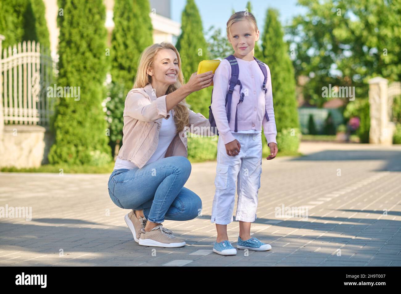 Mama fixiert einen Rucksack auf dem Rücken ihrer Kinder Stockfoto