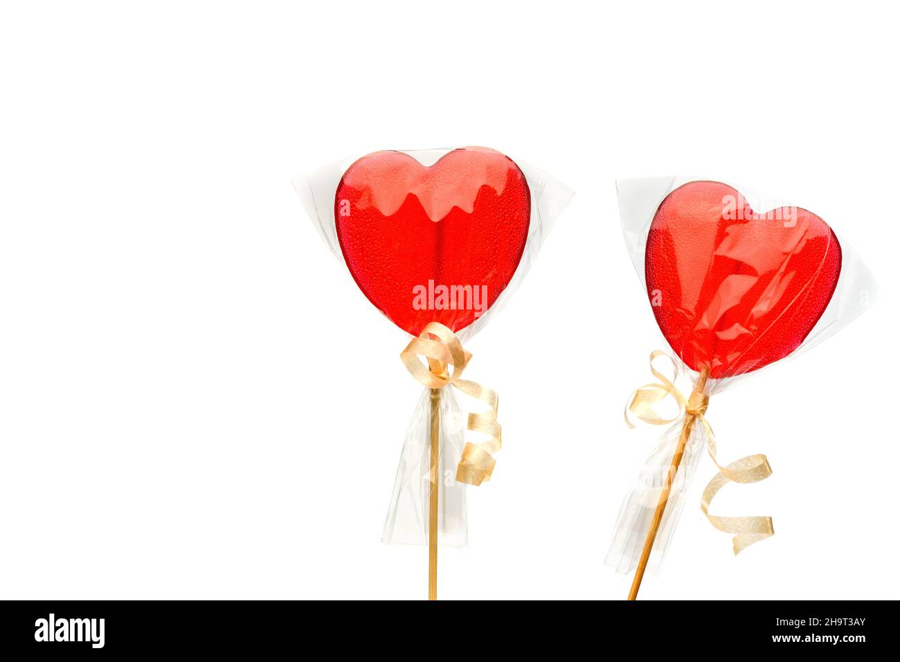 Lollipop. Zwei rote herzförmige Lutscher in transparenter Verpackung auf weißem, isoliertem Hintergrund zum Valentinstag. Isolieren. Stockfoto