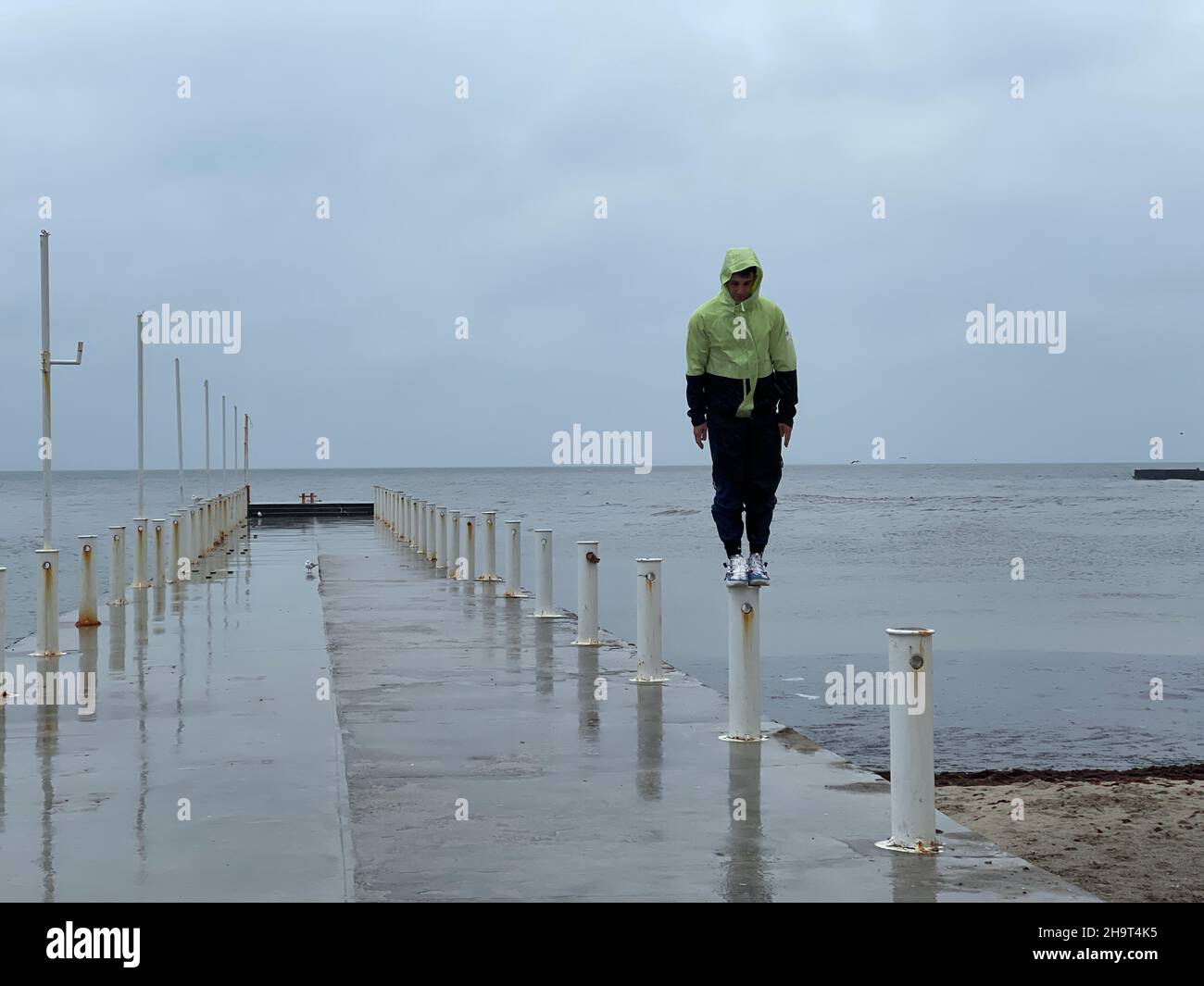 Mann, der auf einer kleinen Säule auf dem Pier im Meer steht Stockfoto