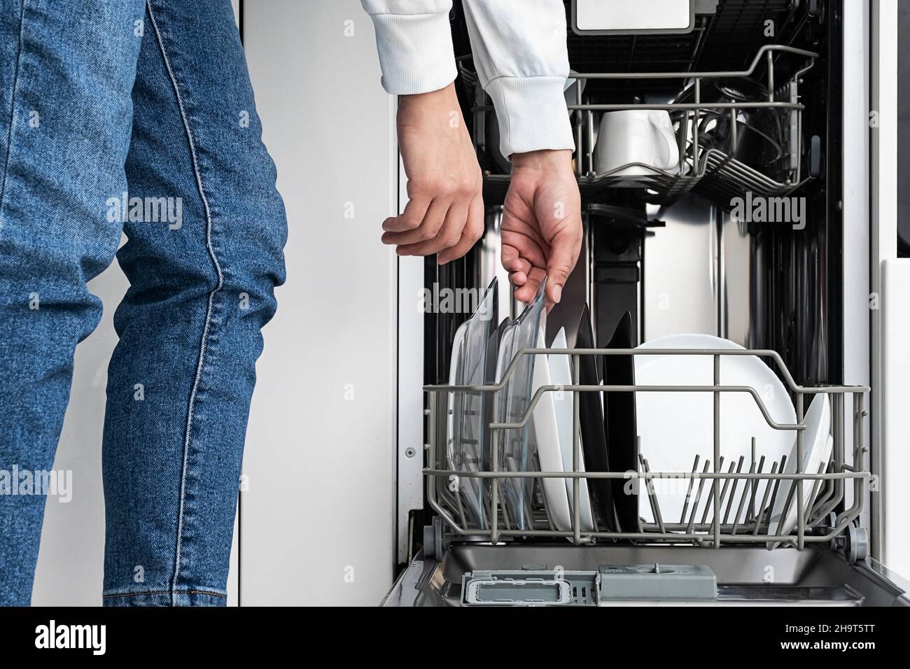 Frau macht Geschirr in der Spülmaschine zu Hause. Reinigen Sie die Teller nach dem Waschen der modernen Küche mit Geschirrspüler. Hausarbeit. Stockfoto