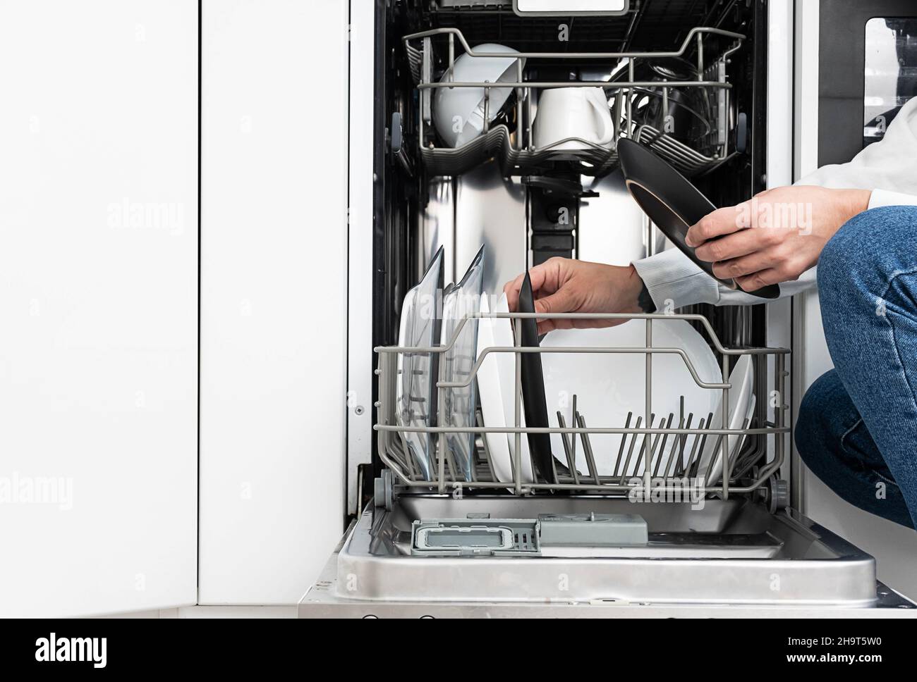 Frau macht Geschirr in der Spülmaschine zu Hause. Reinigen Sie die Teller nach dem Waschen der modernen Küche mit Geschirrspüler. Hausarbeit. Stockfoto