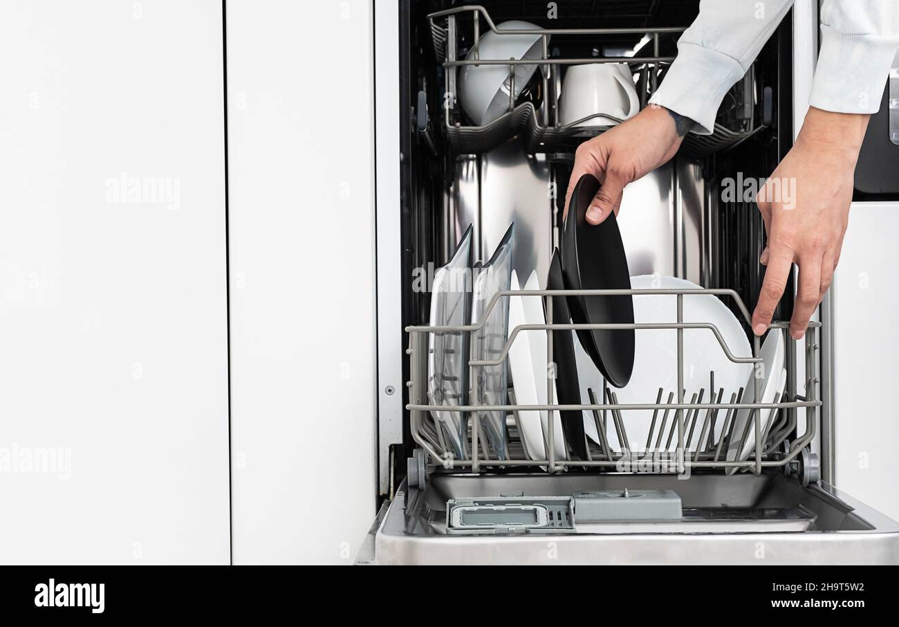 Frau macht Geschirr in der Spülmaschine zu Hause. Reinigen Sie die Teller nach dem Waschen der modernen Küche mit Geschirrspüler. Hausarbeit. Stockfoto