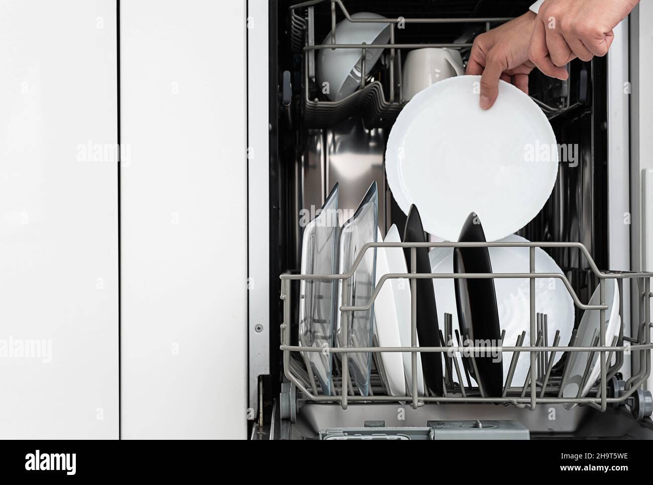 Frau macht Geschirr in der Spülmaschine zu Hause. Reinigen Sie die Teller nach dem Waschen der modernen Küche mit Geschirrspüler. Hausarbeit. Stockfoto