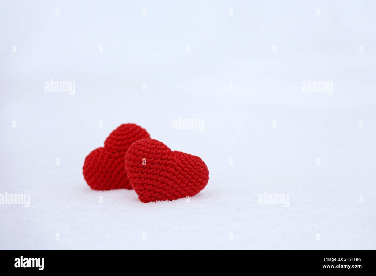 Liebe Herzen im Schnee, Winter Natur. Valentinskarte, zwei gestrickte rote Symbole der Liebe, Hintergrund für romantische Veranstaltung, Weihnachtsfeier Stockfoto