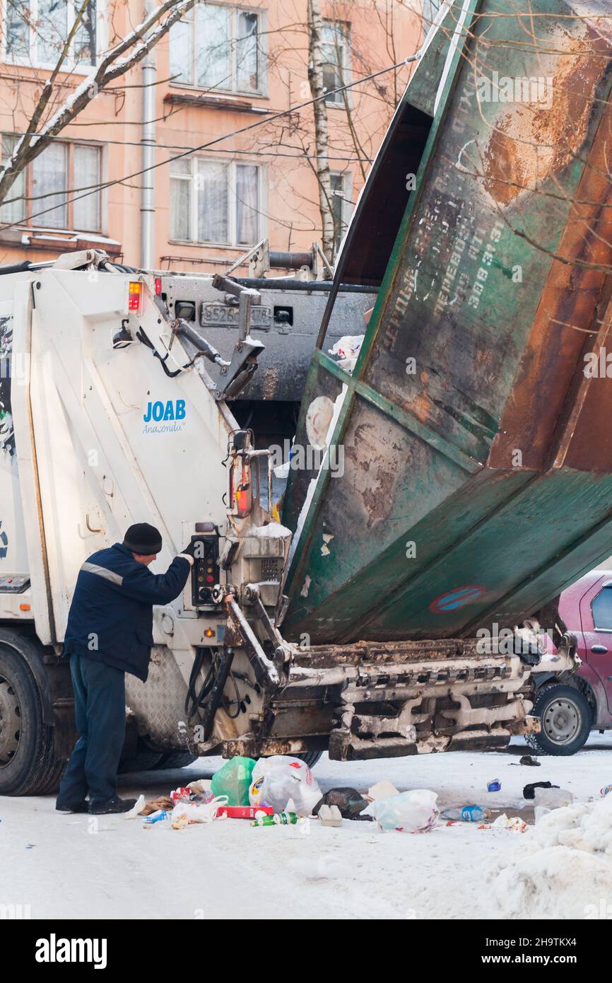 Saint-Petersburg, Russland - 27. Februar 2018: Man betreibt das Verladen von Müll von einem Straßencontainer in einen Frachtführer an einem Wintertag Stockfoto