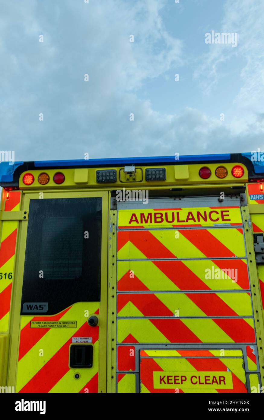 Rückansicht eines Notarztwagens der NHS unter einem stürmisch bedrohlichen Himmel, Rettungswagen mit grauem Himmel über dem Fahrzeug, Reaktionszeiten Stockfoto