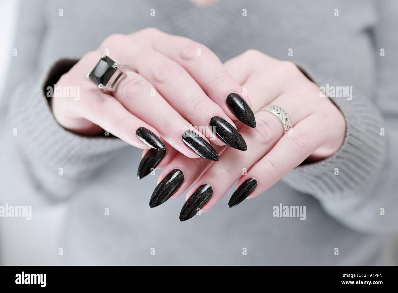 Weibliche Hand mit langen Nägeln und schwarzer Maniküre hält eine Flasche  Nagellack Stockfotografie - Alamy