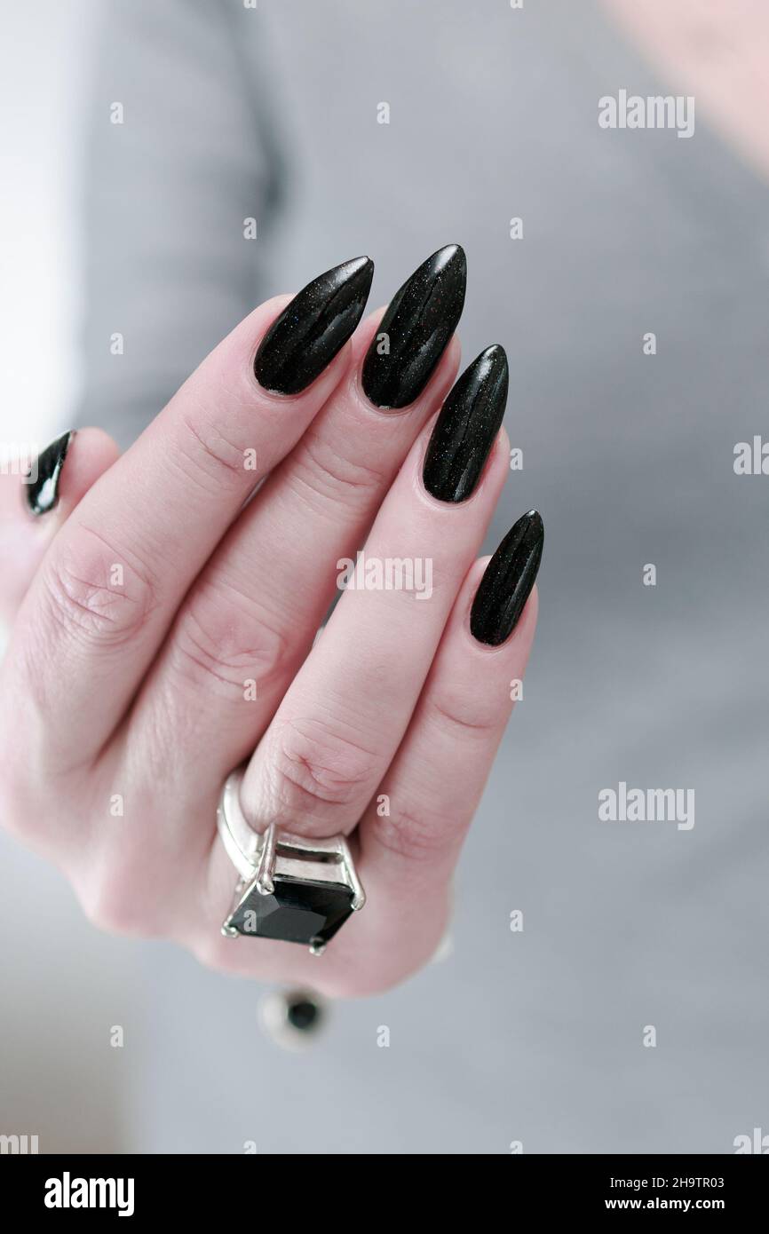 Weibliche Hand mit langen Nägeln und schwarzer Maniküre hält eine Flasche  Nagellack Stockfotografie - Alamy
