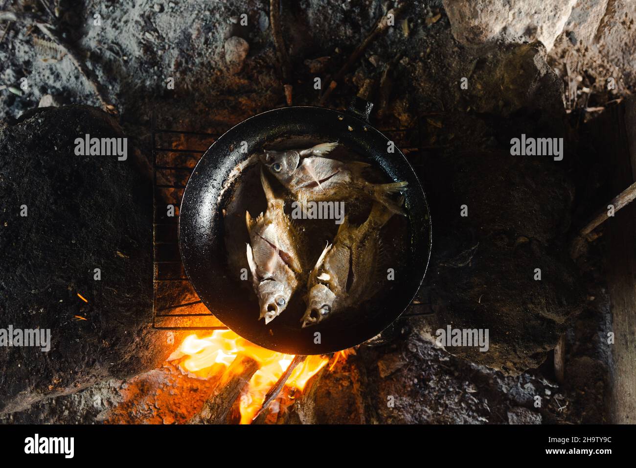 Braten von Fisch in einer Pfanne mit einem Feuer Stockfoto