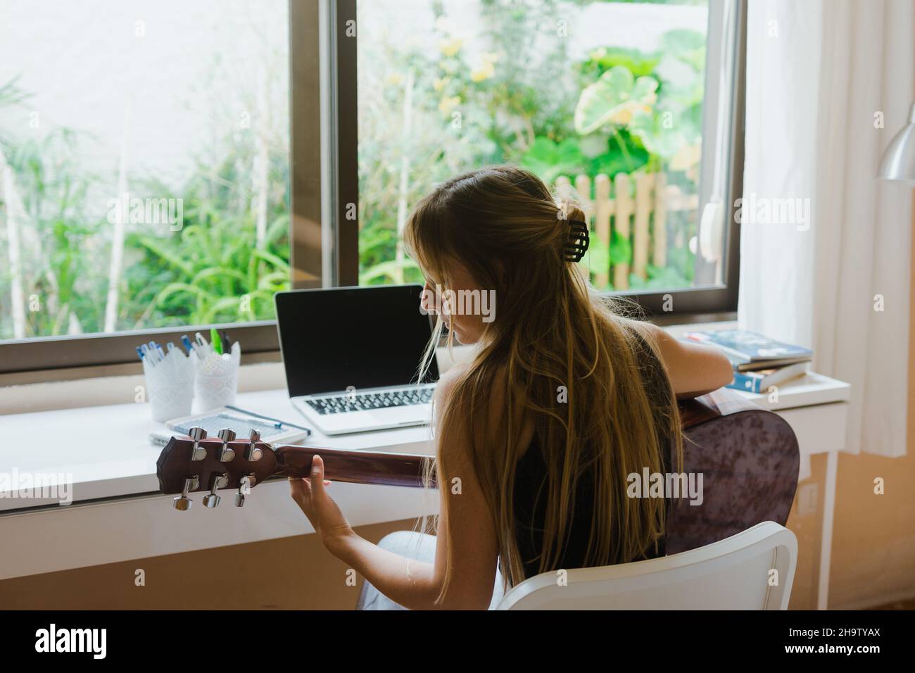 Mädchen, die Gitarre in ihrem Zimmer lernt. Stockfoto