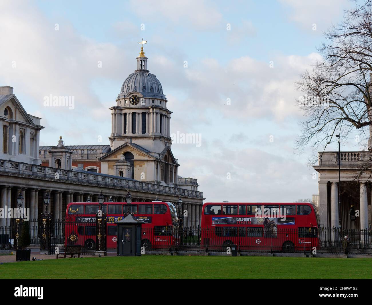 London, Greater London, England, Dezember 04 2021: Zwei rote Busse vor der Greenwich University aus Sicht des Greenwich Park. Stockfoto