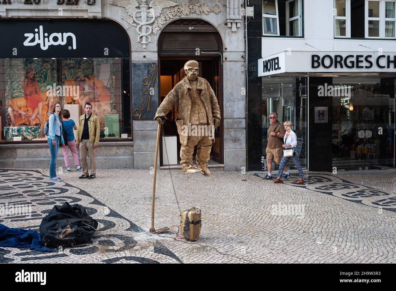 '11.06.2018, Portugal, , Lissabon - Passanten staunen über den Trick eines scheinbar schwebenden Straßenkünstler in Gold gekleidet in einer Fußgängerzone in der Stockfoto