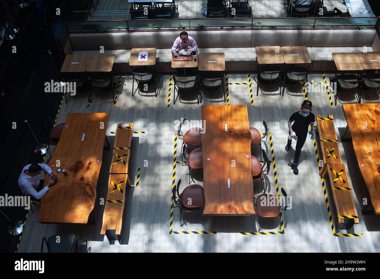 '15.09.2021, Singapur, , Singapur - die Menschen essen in einem Restaurant in einem Einkaufszentrum von Raffles Place, wo Tische und Bänke mit Klebeband für li markiert sind Stockfoto