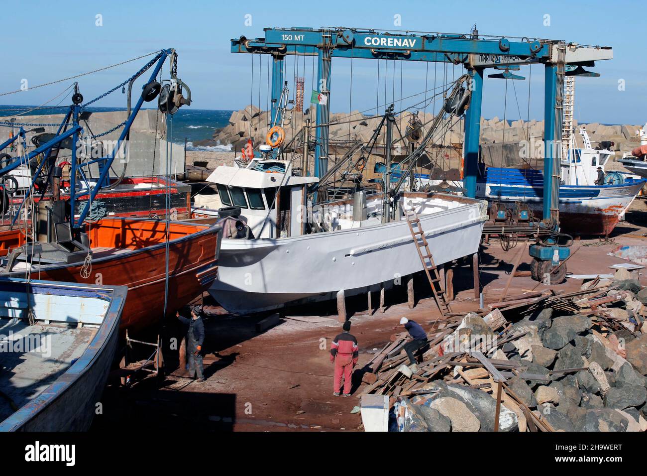 (211208) -- ZEMMOURI (ALGERIEN), 8. Dezember 2021 (Xinhua) -- Arbeiter unterhalten am 8. Dezember 2021 Fischereifahrzeuge auf einer Reparaturwerft im Hafen von Zemmouri, etwa 50 Kilometer östlich von Algier, Algerien. In den letzten Jahren hat die algerische Regierung die Entwicklung der Fischerei gefördert und indirekt die Entwicklung der Fischereifahrzeuge-Instandhaltungsindustrie gefördert. (Xinhua) Stockfoto