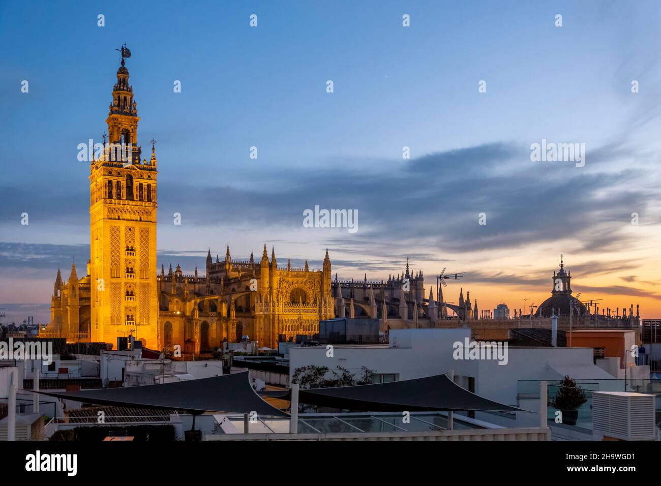 Blick auf den Sonnenuntergang von einem Dach mit Blick auf Sevilla, Spanien, mit dem Giralda-Turm und der großen Kathedrale von Sevilla in Blick auf die Skyline am frühen Abend Stockfoto