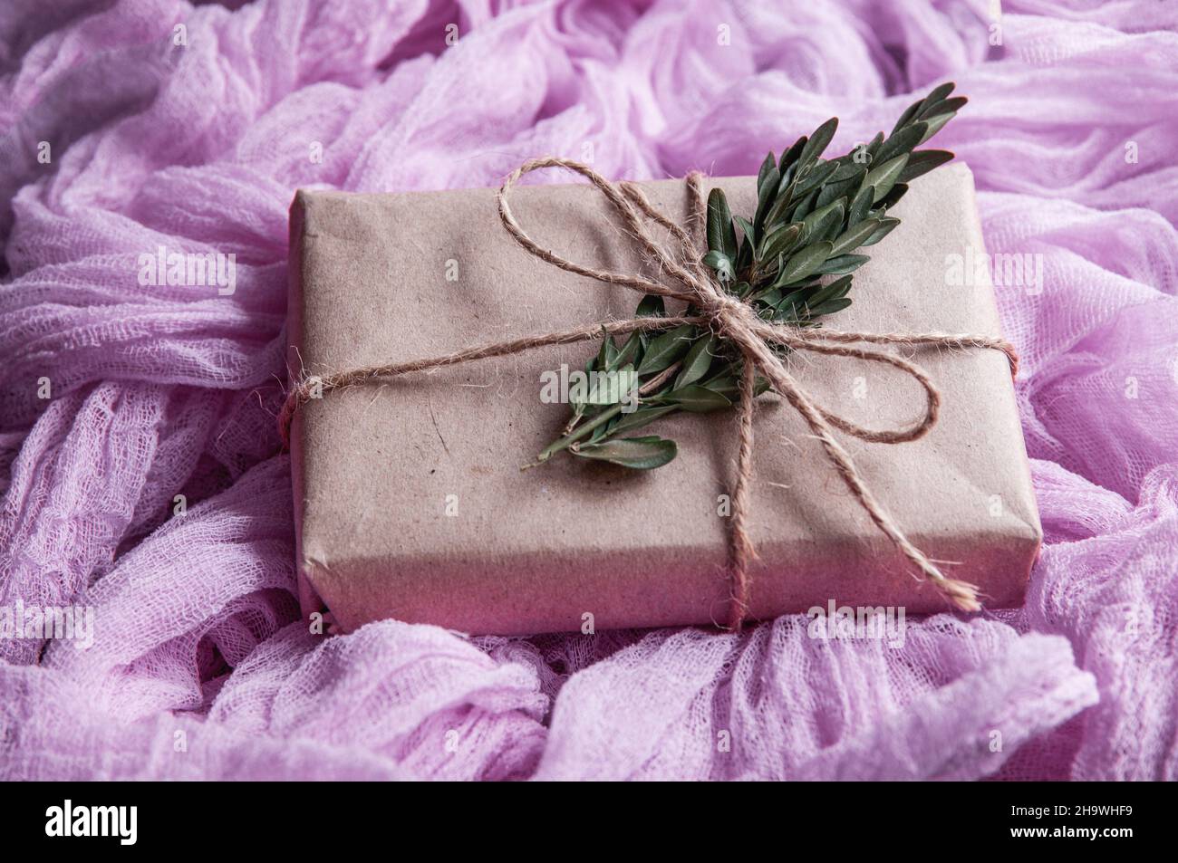 geschenkschachtel aus kraftpapier neben einer Vintage-Tischdecke, handbemalte rosa Gaze. Gaze-Läufer im Boho-Stil, rustikale Tischdecke für Hochzeitsdekor Stockfoto