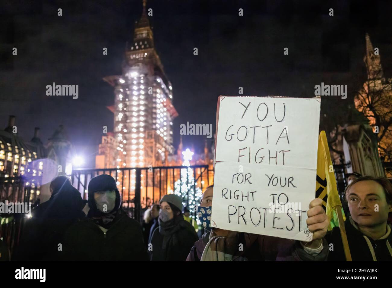 Eine Protesterin hält während der Demonstration ein Plakat, auf dem sie ihre Meinung zum Ausdruck bringt. Die Demonstranten versammelten sich zunächst, um gegen das Gesetz über Polizei, Kriminalität, Verurteilung und Gerichte zu protestieren, das sich derzeit in zweiter Lesung befindet. Wenn das Gesetz verabschiedet würde, würde es eine erhebliche Einschränkung des Protestrechts bedeuten. Im Zusammenhang mit der Pressekonferenz zur Reaktion Großbritanniens auf die Omicron-Variante des Covid-Virus kündigte Boris Johnson an, dass der „Plan B“ ab Montag stattfinden wird. Das bedeutet, dass die Menschen von zu Hause aus arbeiten müssen, dass sie Gesichtsmasken in Innenräumen tragen müssen und dass sie Impfpass haben Stockfoto