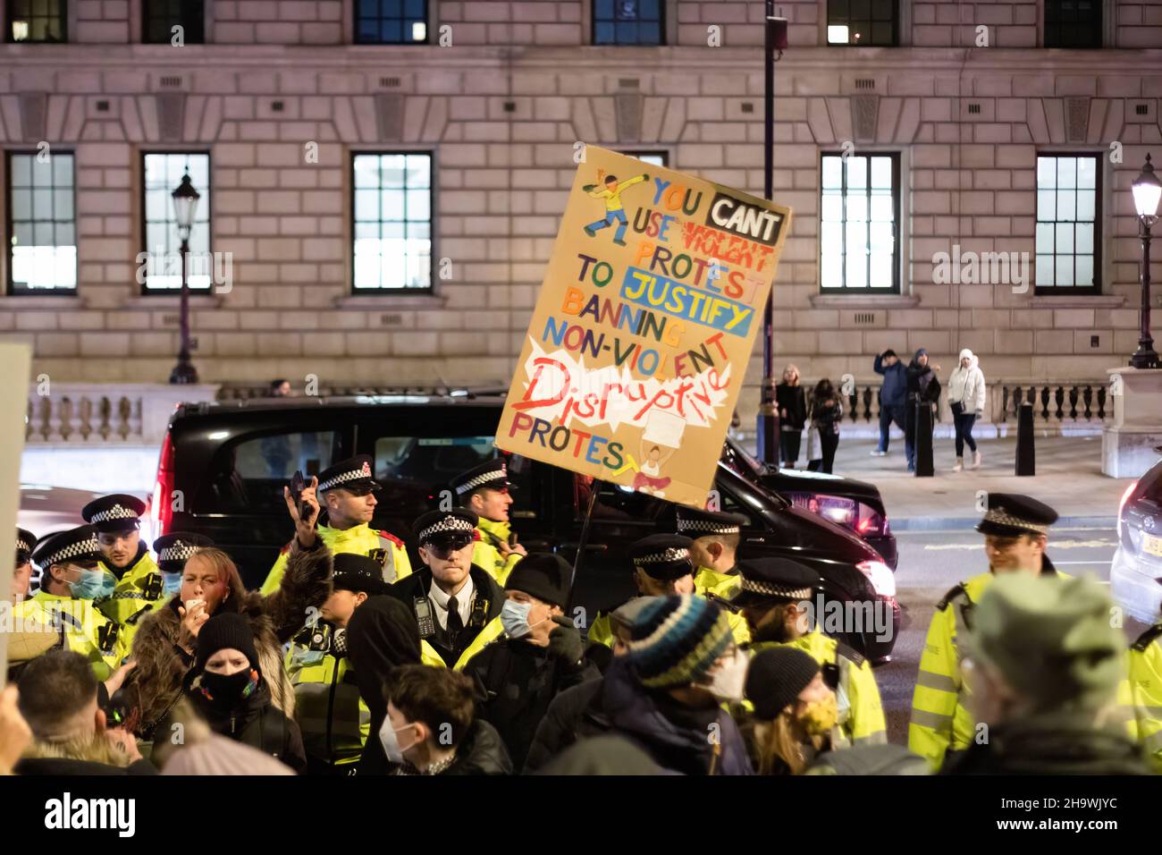 Ein Protestler hält während der Demonstration ein Plakat mit seiner Meinung. Die Demonstranten versammelten sich zunächst, um gegen das Gesetz über Polizei, Kriminalität, Verurteilung und Gerichte zu protestieren, das sich derzeit in zweiter Lesung befindet. Wenn das Gesetz verabschiedet würde, würde es eine erhebliche Einschränkung des Protestrechts bedeuten. Im Zusammenhang mit der Pressekonferenz zur Reaktion Großbritanniens auf die Omicron-Variante des Covid-Virus kündigte Boris Johnson an, dass der „Plan B“ ab Montag stattfinden wird. Das bedeutet, dass die Menschen von zu Hause aus arbeiten müssen, dass sie Gesichtsmasken in Innenräumen tragen müssen und dass sie Impfpass haben Stockfoto