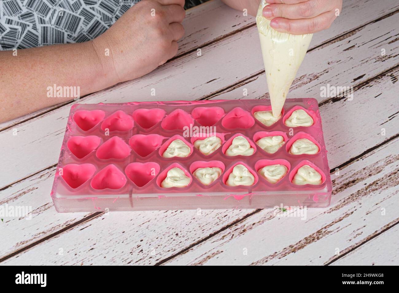 Süßwaren mit einer Süßwarendüse Schokolade mit weißer Schokoladenganache füllen. Stockfoto
