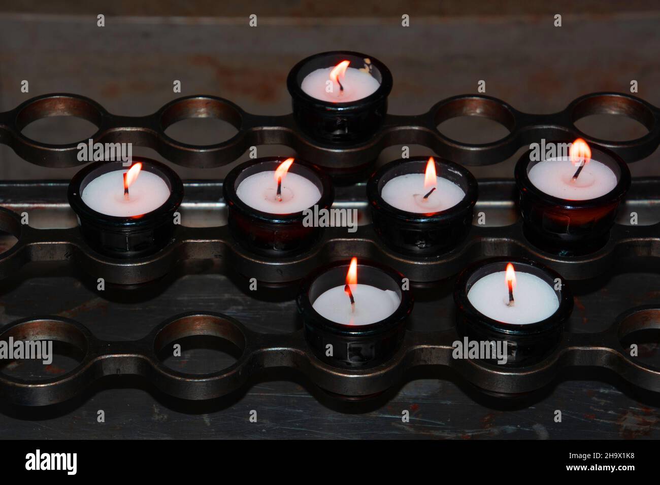 Brennende Gedächtniskerzen mit warmen Flammen in einer Kirche Stockfoto