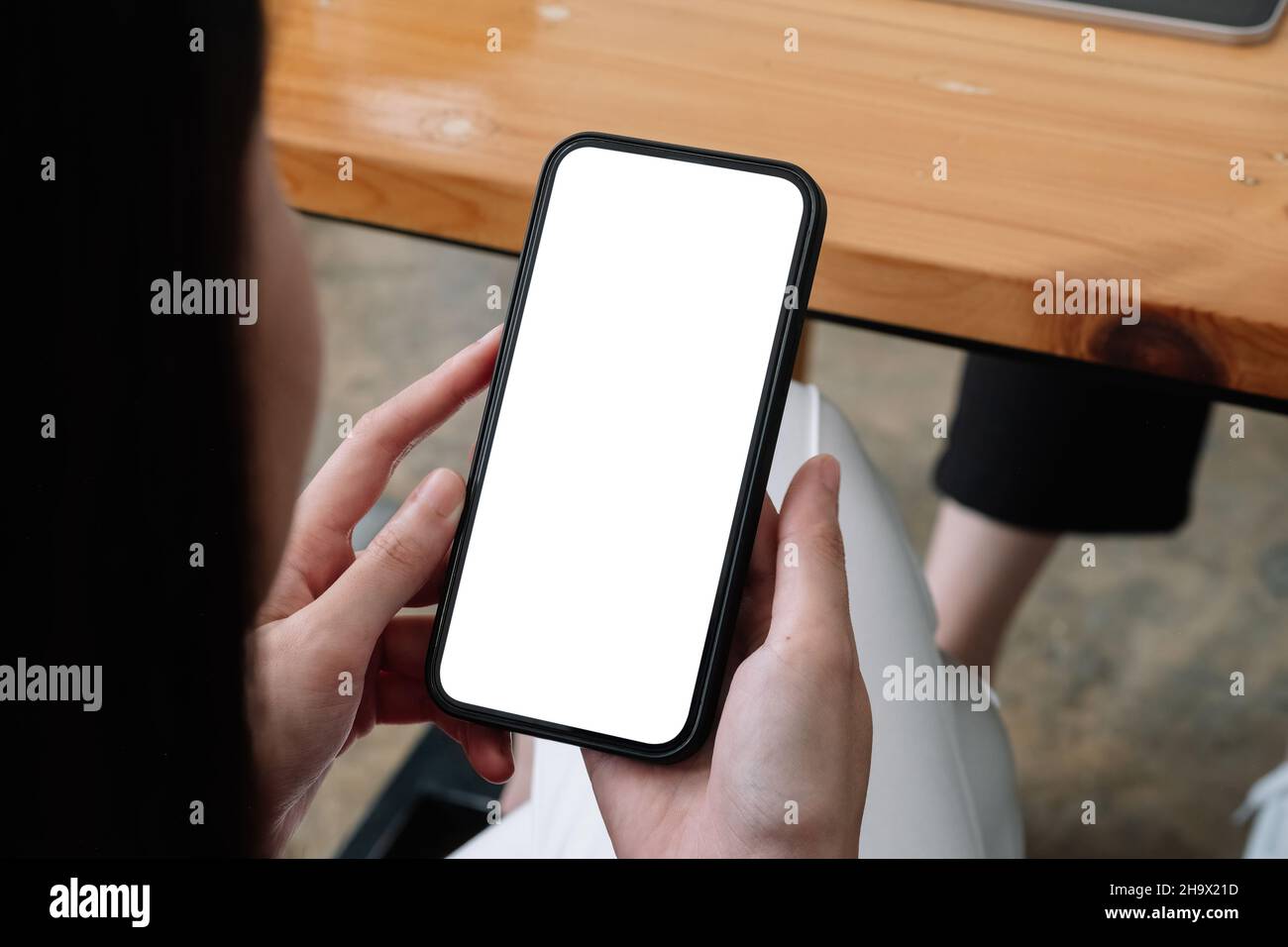 Handy in Frauenhand mit weißem Bildschirm, weiblich mit Mobiltelefon mit leerem Bildschirm für SMS, Chat. Stockfoto