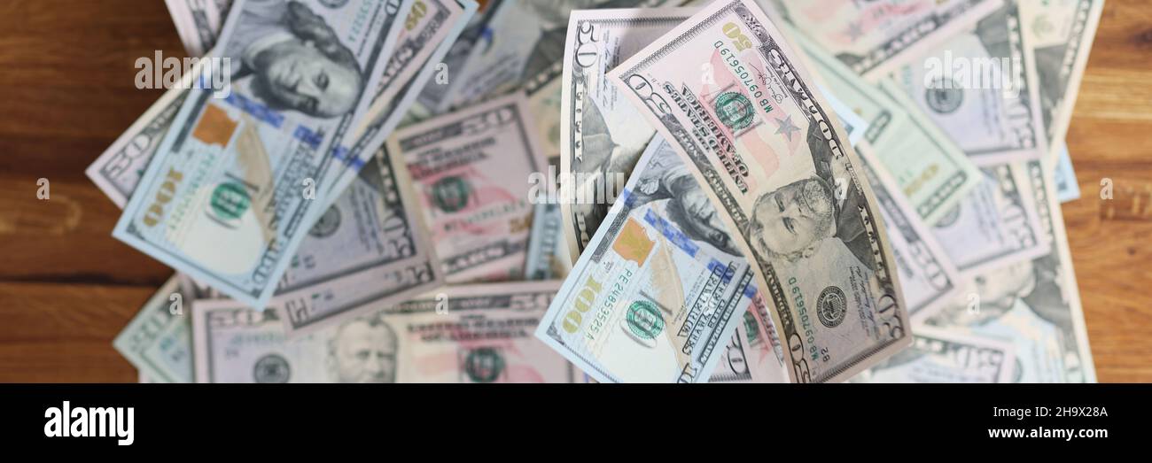 Viele verschiedene Dollarscheine, die auf einem Holztisch liegen, machen den Hintergrund aus der Nähe Stockfoto