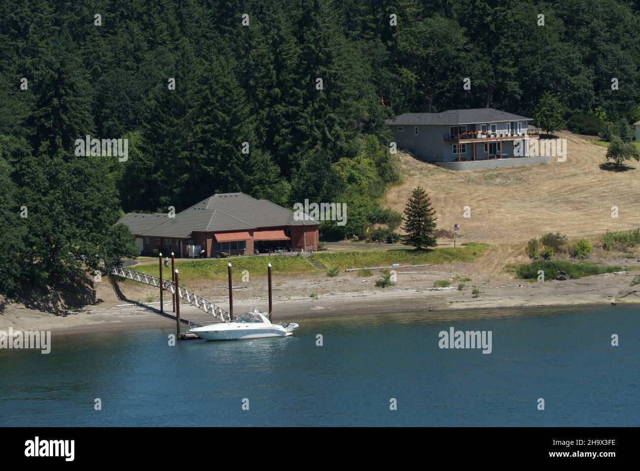 Familienhäuser mit privater Anlegestelle mit Brücke und Motorboot vom Handelsschiff aus beobachtet. Stockfoto