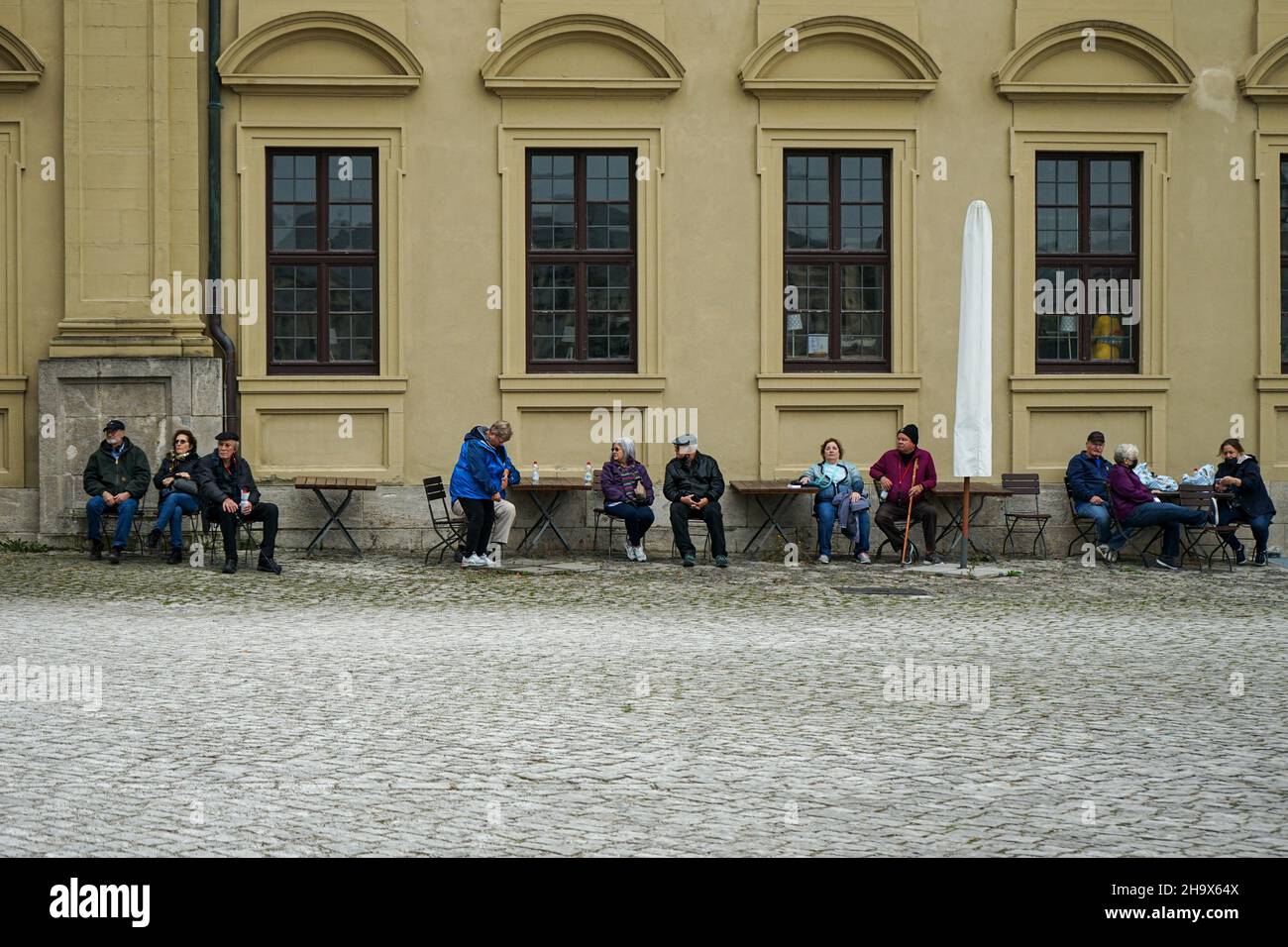 Eine Gruppe älterer Menschen ruht auf den Stühlen eines Freiluftcafés in der Würzburger Residenz. Stockfoto