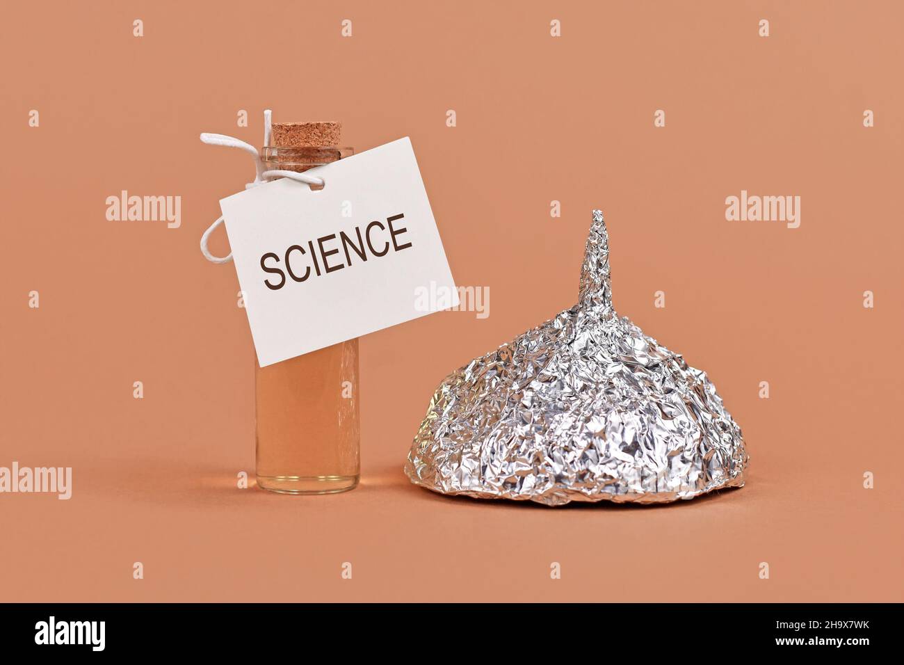Konzept zur Bekämpfung von Verschwörungstheorien mit der Wissenschaft mit einem Kinfoil-Hut und einer Kurflasche Stockfoto