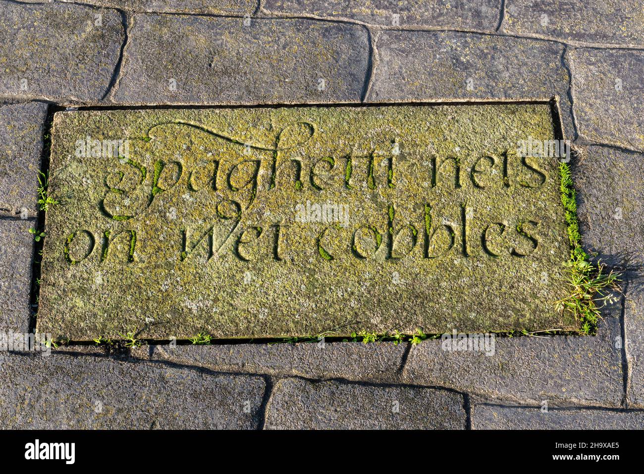 Geschnitzte Steinplatte in der Hafenmauer von Maryport mit den Worten „Spaghettinetze auf nassen Kopfsteinpflaster“, Cumbria, England, Großbritannien Stockfoto