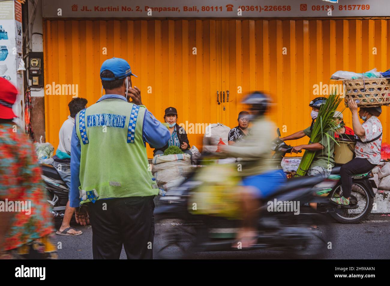 Ein Mann, der den Verkehr auf der belebten Straße von Denpasar organisiert Stockfoto