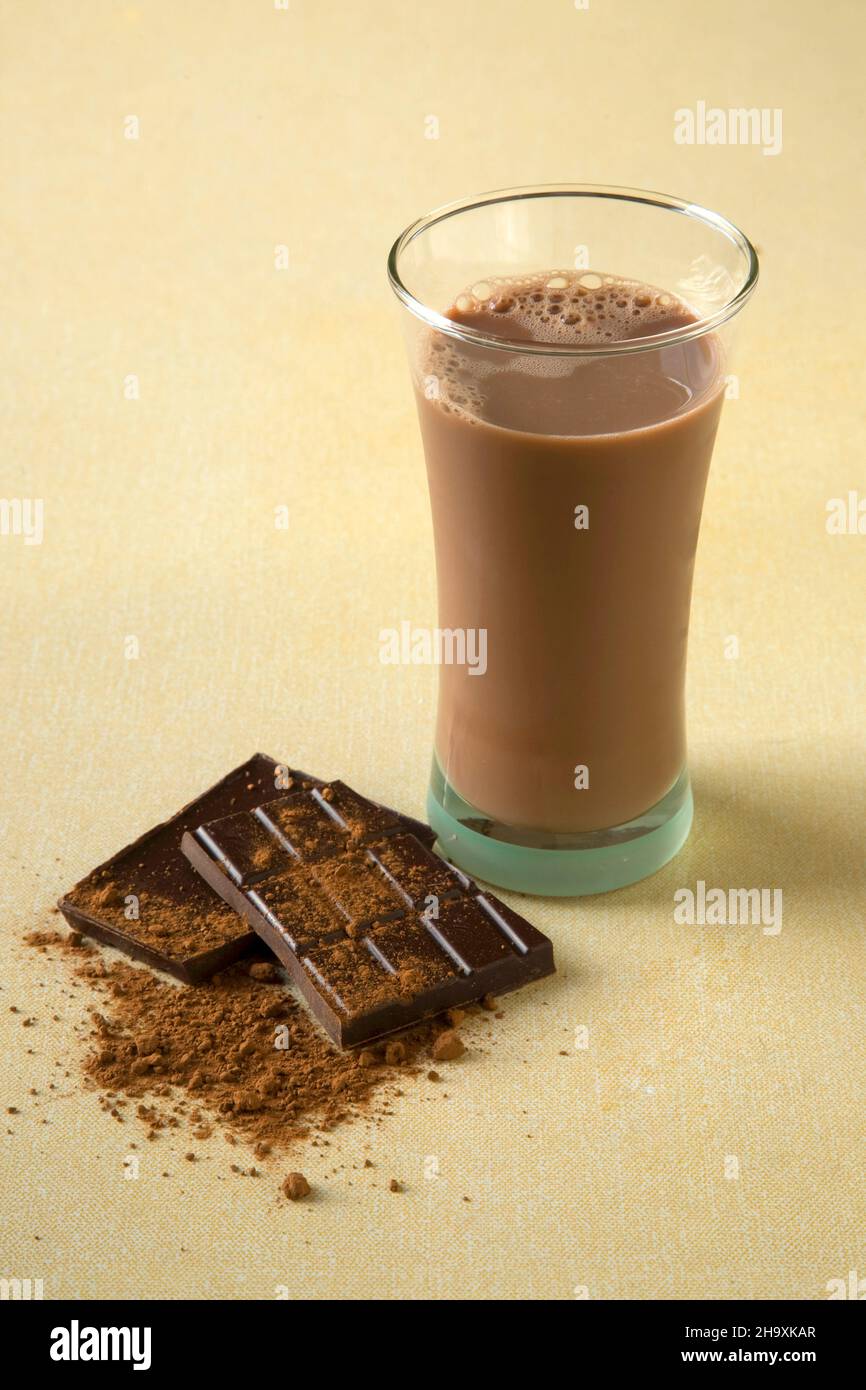 Ein Glas Schokoladenmilch neben Schokolade und Kakaopulver Stockfoto