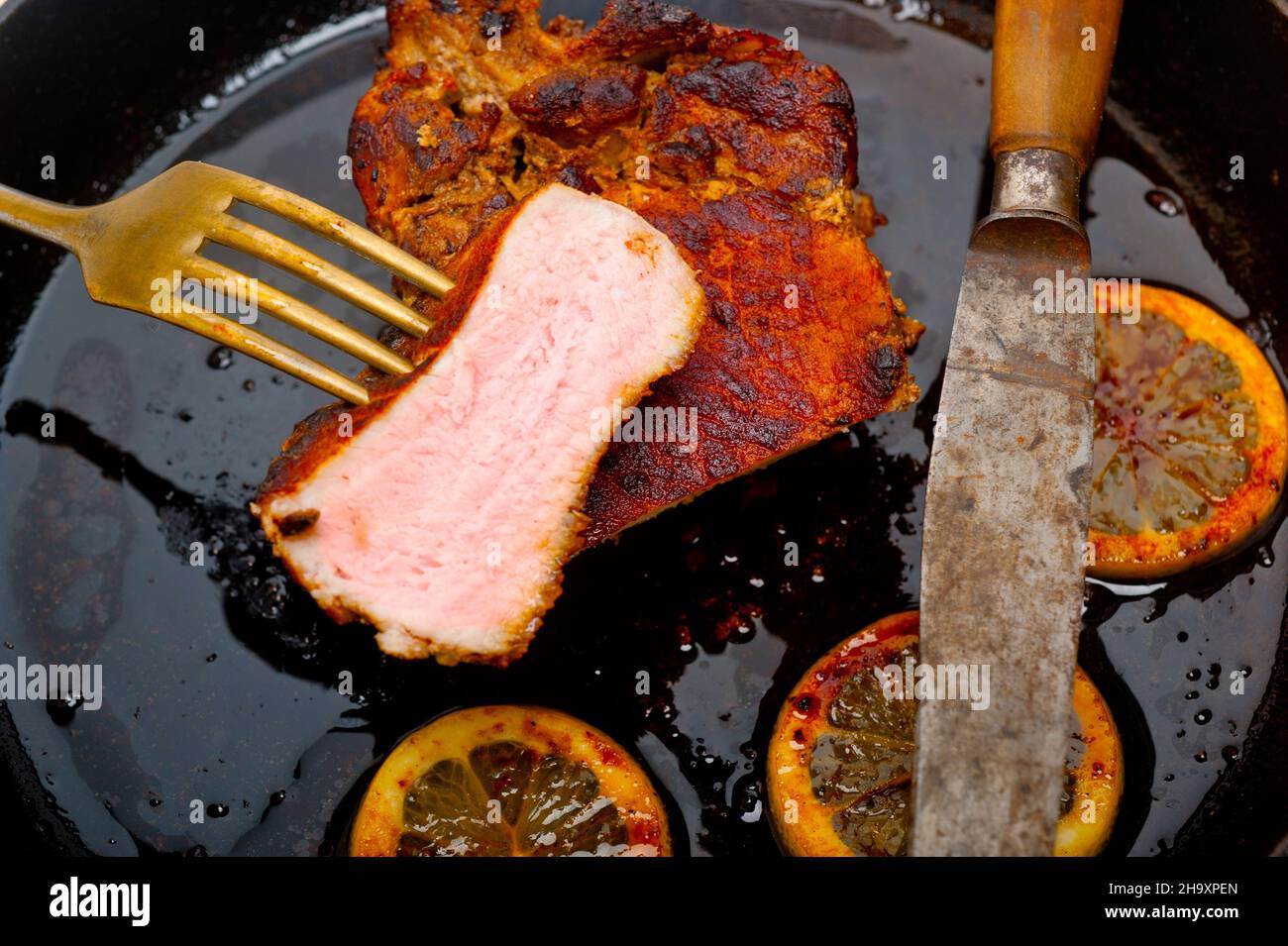 Schweinekotelett auf eisernen Pfanne mit Zitrone und Gewürze Gewürz angebraten Stockfoto
