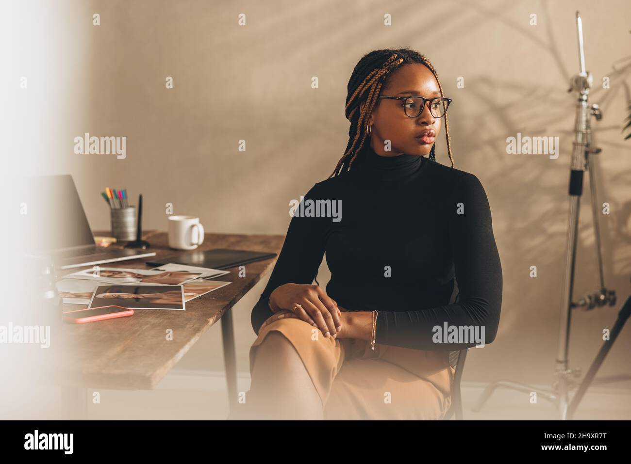 Der junge Fotograf schaut nachdenklich weg. Kontemplative junge Frau denkt an neue Ideen für ihr kreatives Projekt. Junge Fotografin sitt Stockfoto