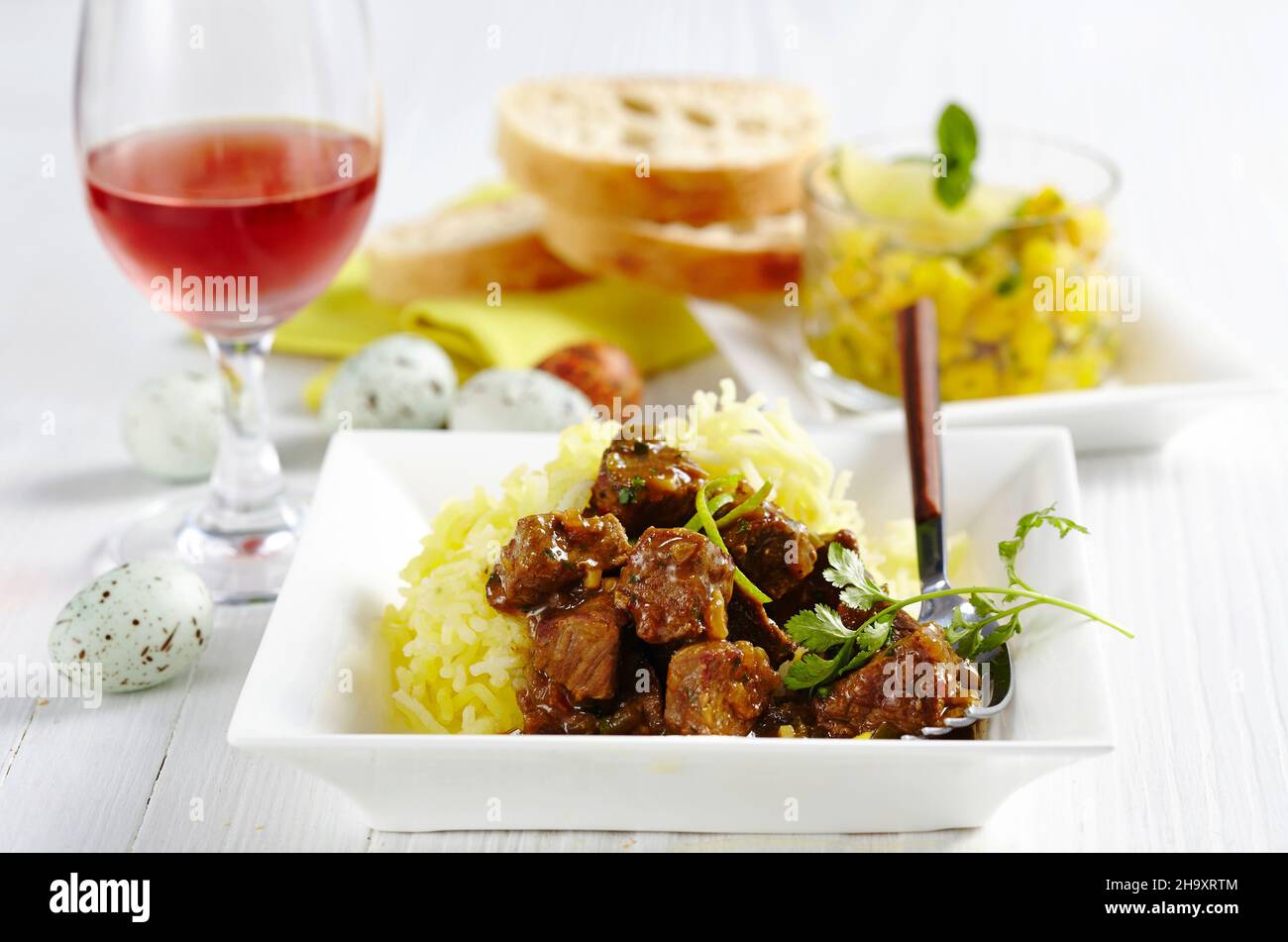 Lammpuhrfleisch auf Kartoffelstroh, serviert mit Mangoeinlagen, Rosenwein und Ostereiern Stockfoto