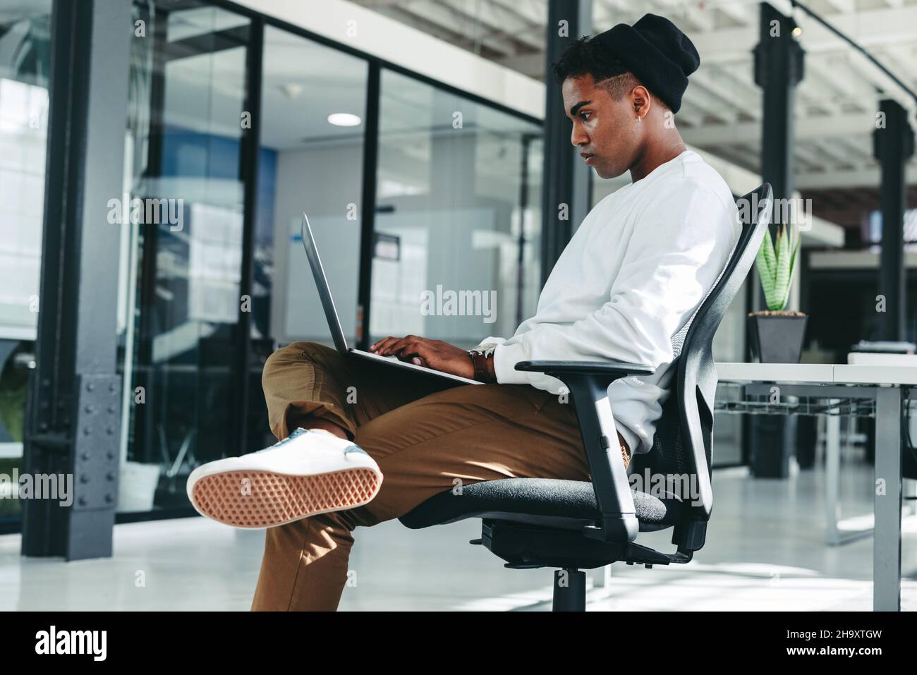 Arbeiten an einem neuen Code. Fokussierter junger Softwareentwickler, der einen Laptop verwendet, während er an einem neuen Projekt in einem Büro arbeitet. Kreativer Geschäftsmann, der alleine sitzt Stockfoto