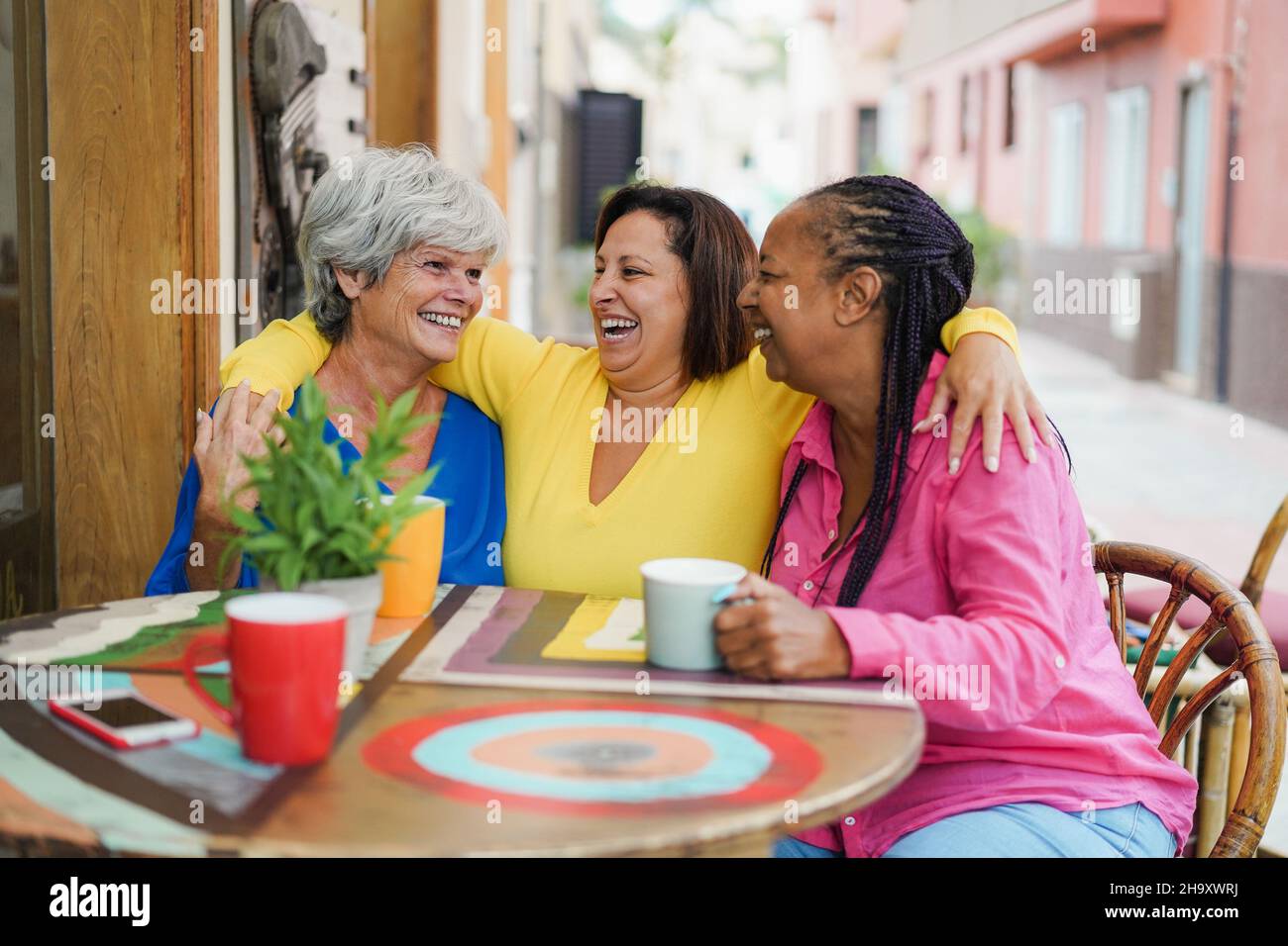 Multirassische ältere Freunde, die sich an der Bar im Freien amüsieren und gemeinsam Kaffee trinken - konzentrieren Sie sich auf das richtige Frauengesicht Stockfoto