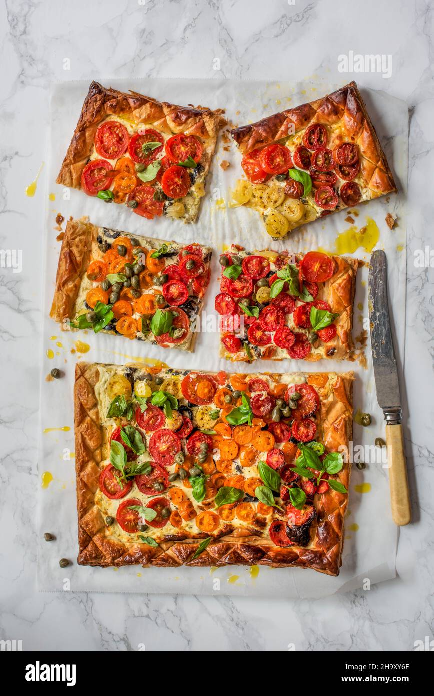 Blätterteig Tomatentorte mit Frischkäse, Oliven, Kapern und Basilikum Stockfoto