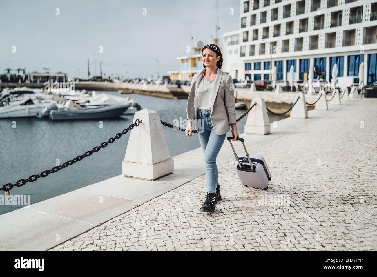 Junge Frau mit Koffer zu Fuß in städtischen Umgebungen, Faro, Portugal Stockfoto