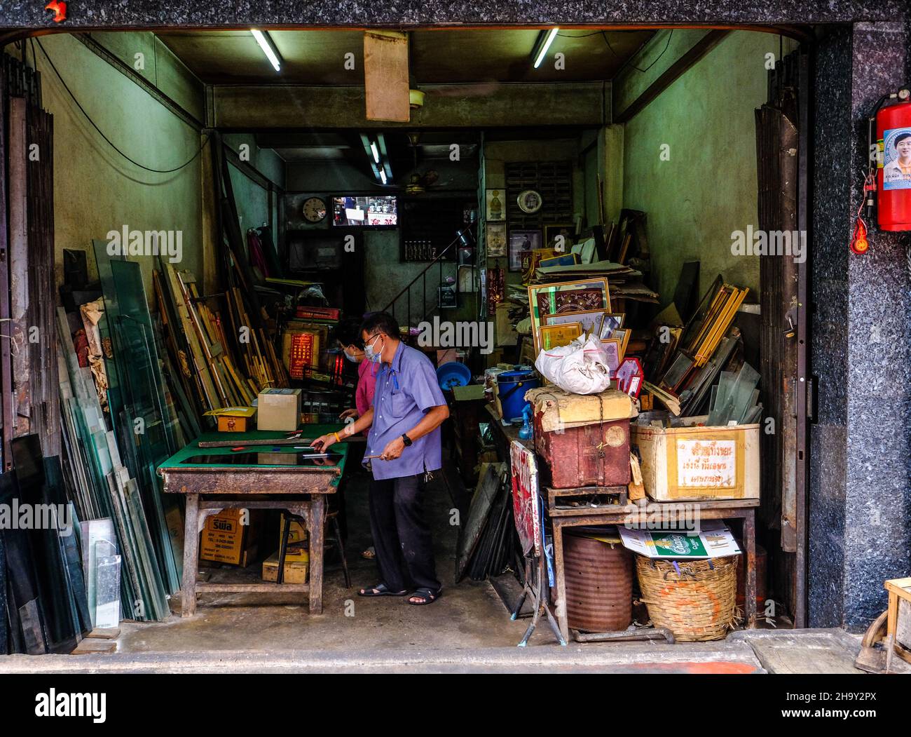 Ein Mann arbeitet in den Räumlichkeiten seines Ladens und macht Bilderrahmen in Bangkok Chinatown, Thailand Stockfoto