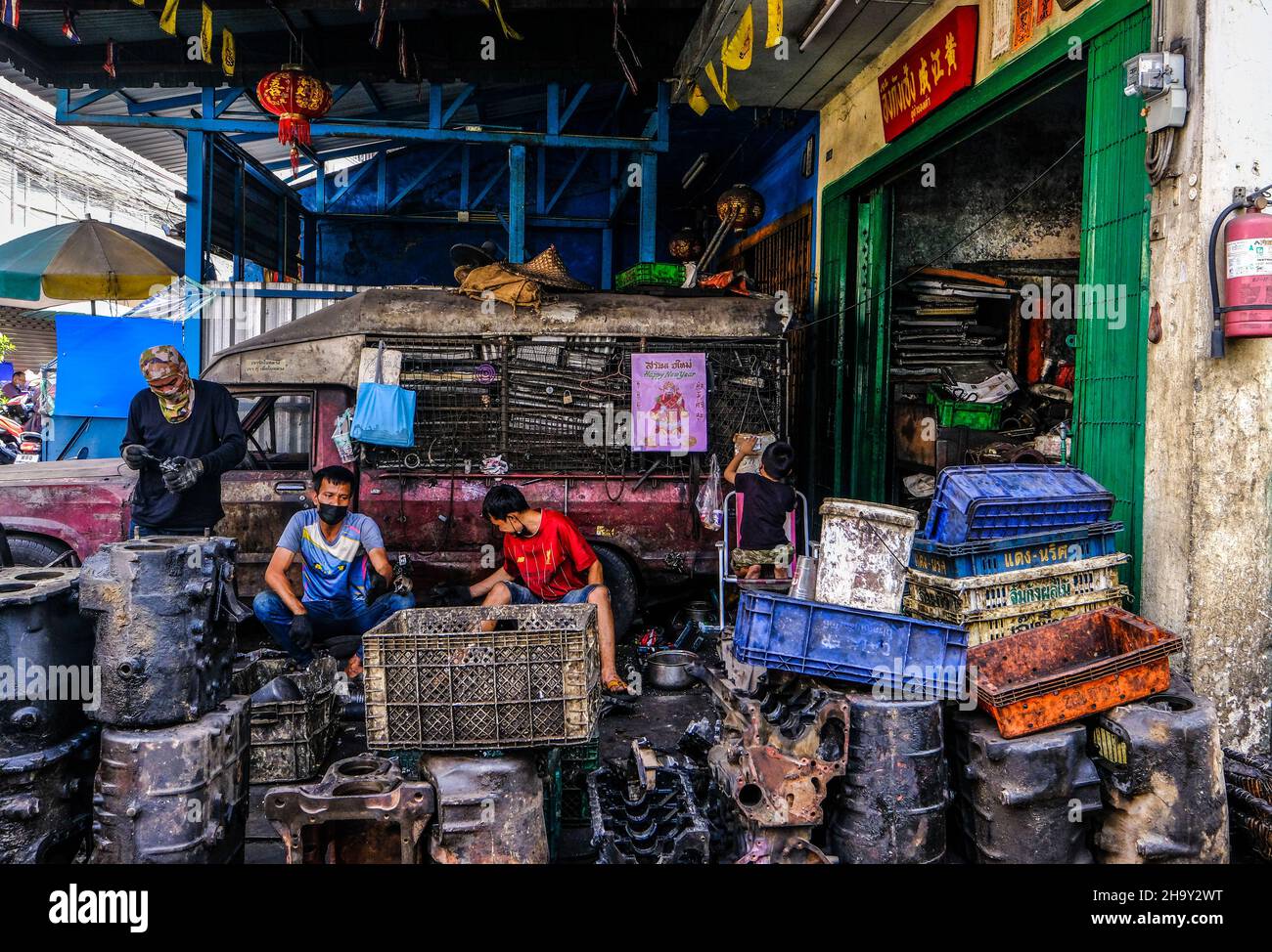 Männer arbeiten außerhalb ihrer Werkstatt und recyceln Autoteile in Talat Noi, Bangkok, Thailand Stockfoto