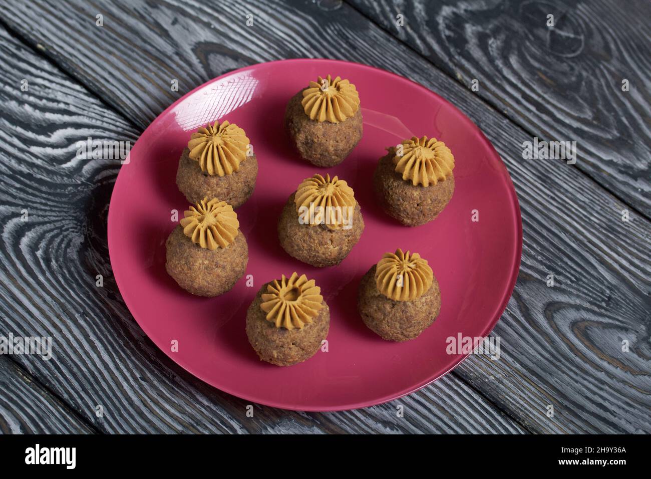 Bananenkuchen mit Buttercreme. Auf einen Teller legen. Auf schwarzen Kiefernbrettern. Nahaufnahme. Stockfoto