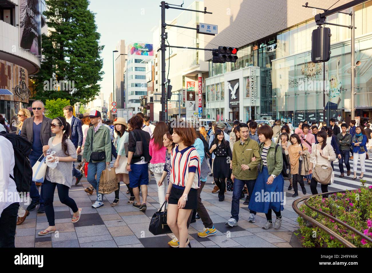 Eine Menge asiatischer Menschen, die in der berühmten und geschäftigen Gegend von Harajuku spazieren und die Straße überqueren. Stockfoto