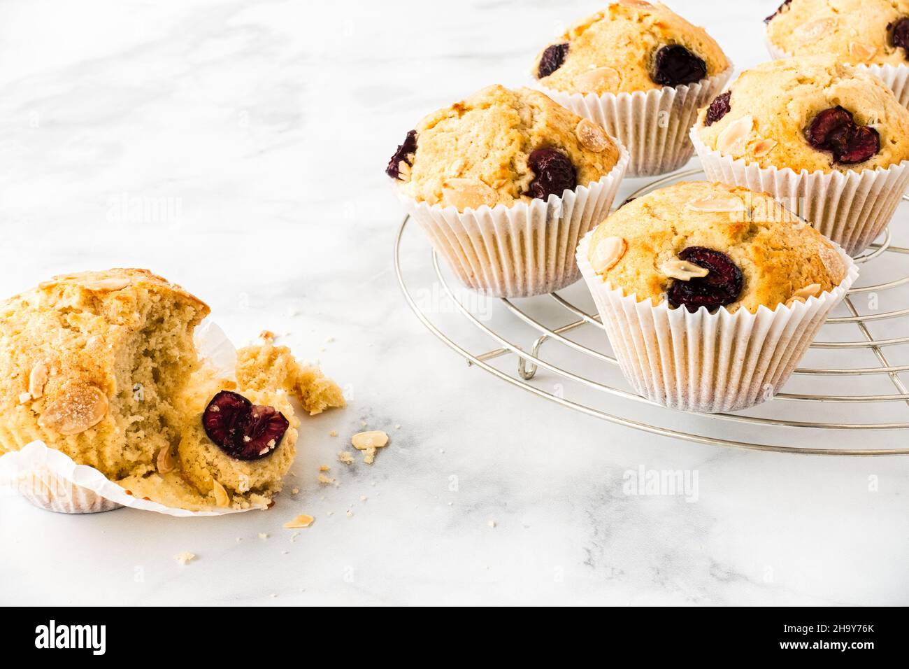 Nahaufnahme von hausgemachten Kirschmuffins auf Kühlregal und weißem Marmor mit Platz für Kopien. Horizontale Version. Low-Angle-Ansicht. Stockfoto