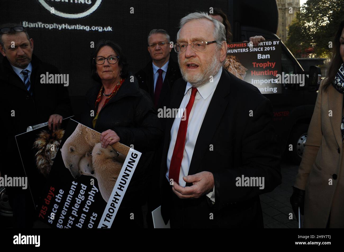 London, Großbritannien. 9th Dez 2021. John Francis Spellar britischer Parlamentsabgeordneter für Warley, ehemals Warley West, seit 1992 Unterstützer der Kampagne. Kampagne zum Verbot der Trophäenjagd, eine neue parteipolitische Fraktion, die neu ins Leben gerufen wurde, zeigt ihr neues digitales Banner vor dem Parlamentsgebäude, das Tiertrophäen auf einem Gepäckkarussell zeigt. Kredit: JOHNNY ARMSTEAD/Alamy Live Nachrichten Stockfoto