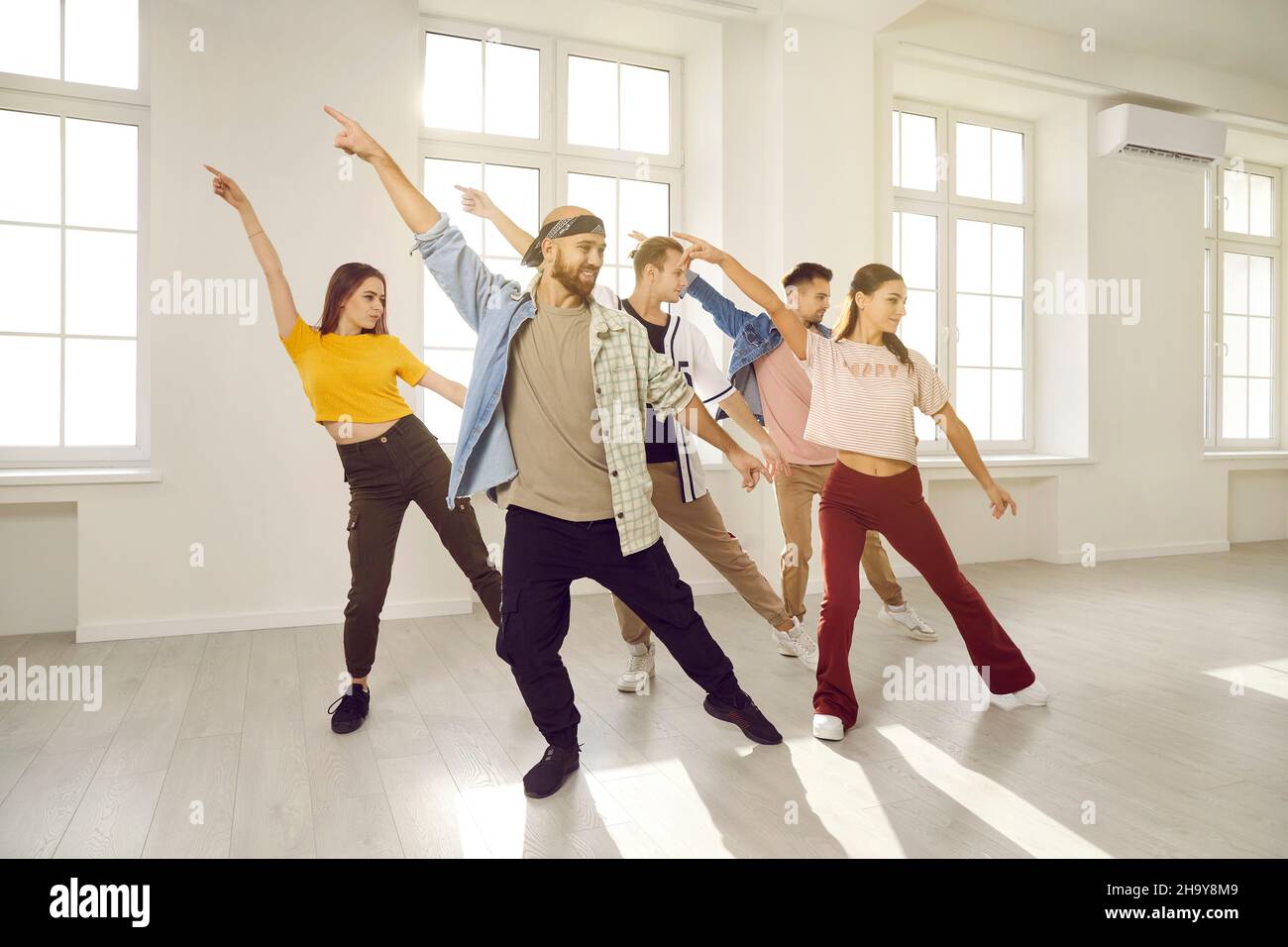 Eine Gruppe von glücklichen jungen Leuten, die einen Tanzkurs mit Tanzlehrer im Fitnessstudio absolvieren Stockfoto